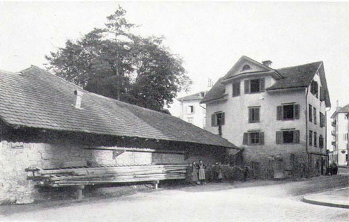 Die Theaterstrasse hinter dem Stadttheater bot 1885 noch kein sehr städtisches Bild. Links ist der Kutschnerstall zu sehen, der zum Seidenhof gehörte. Das abbruchreife Haus dahinter steht an der Stelle der nachmaligen Volksküche (heute Bistro du Théatre). Wiederum dahinter ist auf der linken Seite das Haus des späteren Hotels Konkordia zu erkennen, das 1969 von einem Feuer zerstört und als Geschäftshaus wiederaufgebaut wurde. Die Trottoirecke rechts im Bild gehört zum Restaurant Theaterhalle (später Le Dézaley, heute Zur Ente).